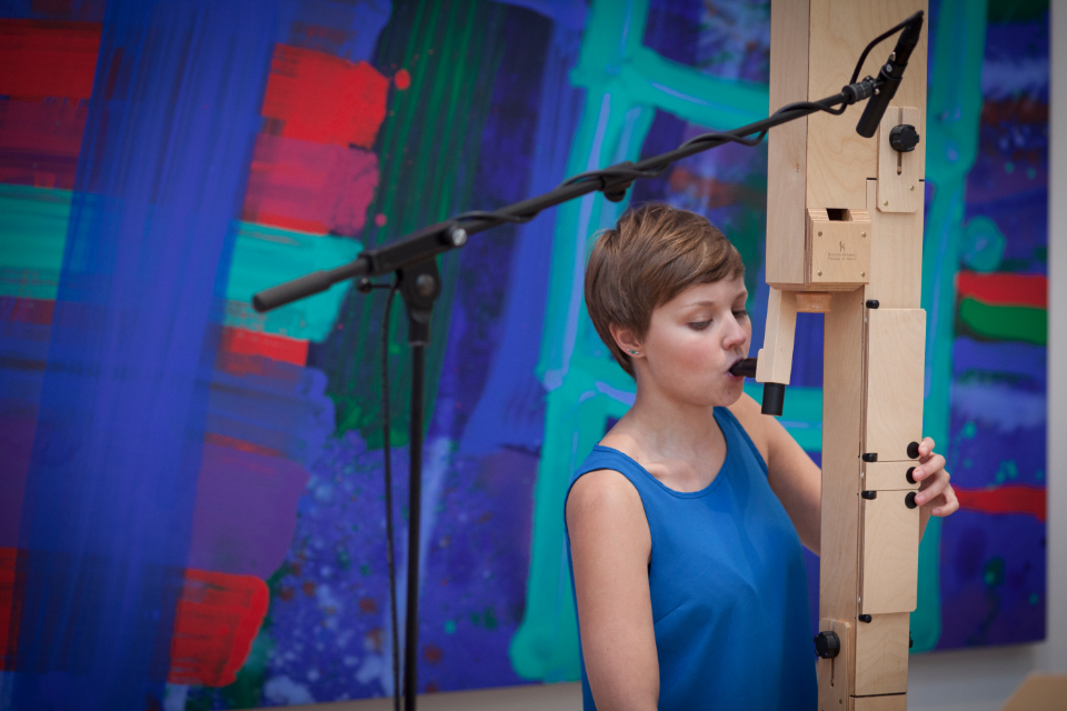 A female student performing on wooden built woodwind instrument, with a microphone above her.
